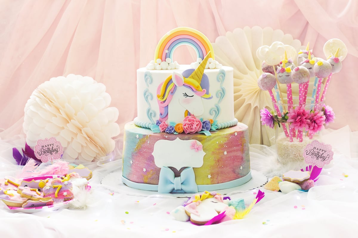 Little girl's birthday party dessert table with unicorn cake, cake-pops, sugar cookies and decorations