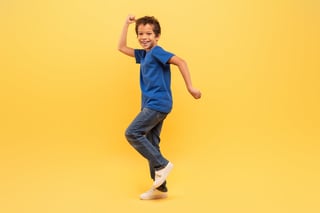 Exuberant boy joyfully dancing against yellow backdrop