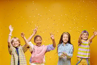 Four little kids jumping to catch confetti