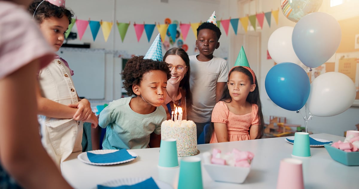 Children celebrating birthday party with cake and balloons