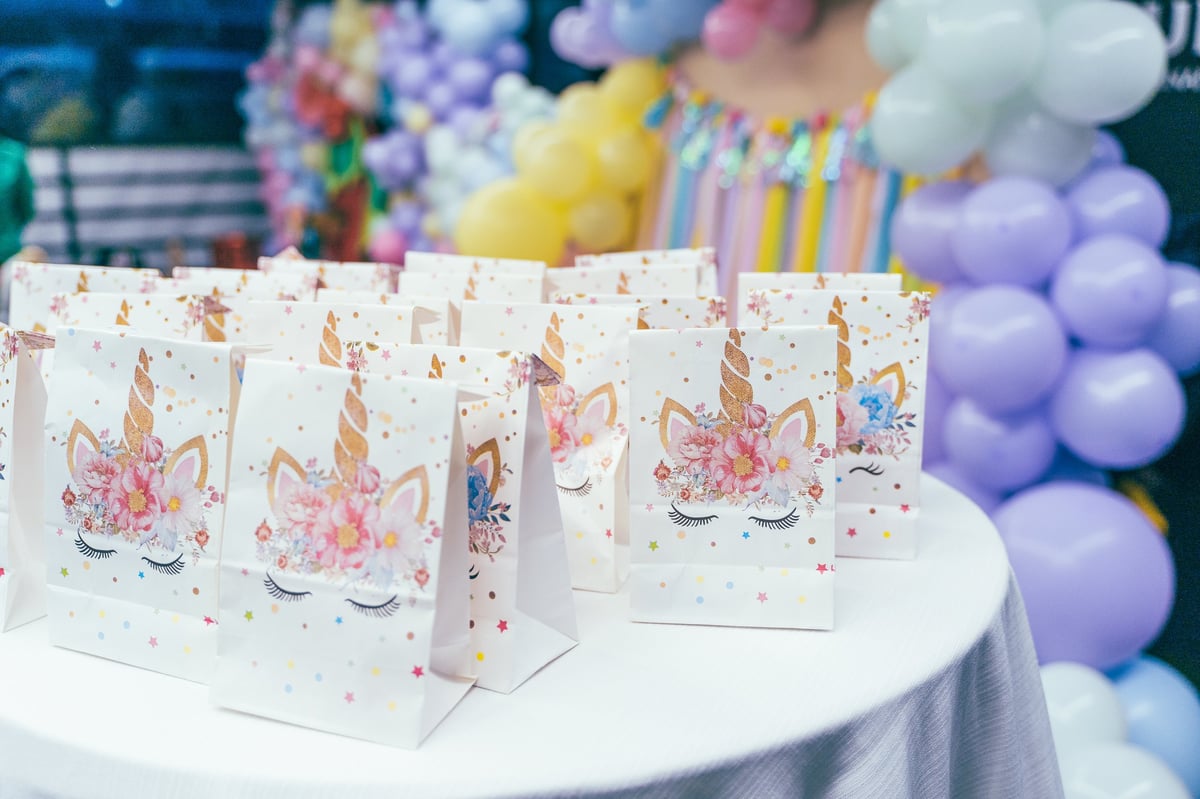 Unicorn-themed gift bags arranged on a round table for a children's birthday party