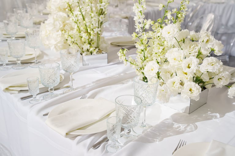 A beautifully arranged table features delicate white flowers in crystal vases. Soft lighting enhances the elegant atmosphere ideal for a special event.