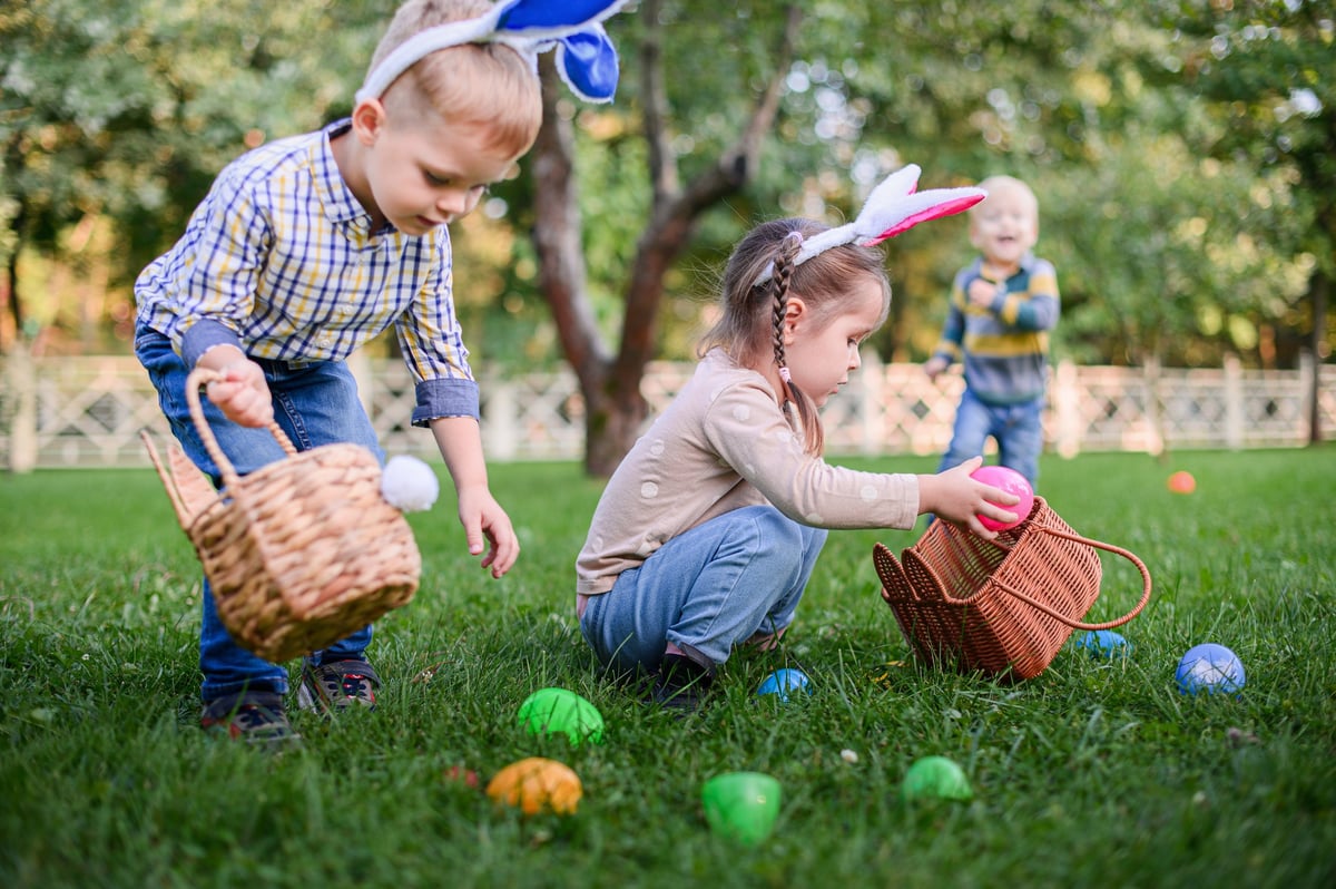 Children hunting for Easter eggs in spring park garden.