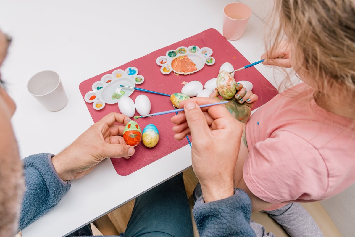 Dad and daughter drawing holiday Easter eggs, man and girl toddler spend time together for crafting hobby painting