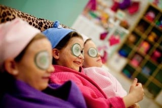 Three children wearing funny novelty glasses with large googly eyes, smiling at the camera in a colorful classroom setting.