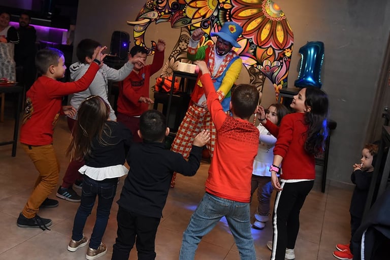 Children in red shirts playing an interactive game or activity indoors with colorful sunflower wall art and blue decorative elements in background